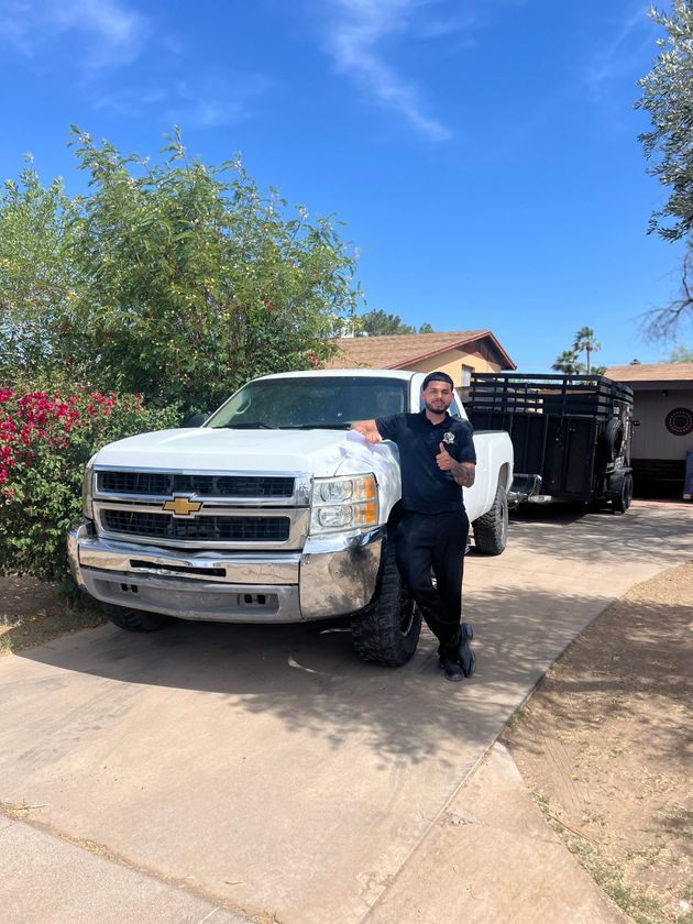 A man is standing next to a white truck in a driveway.