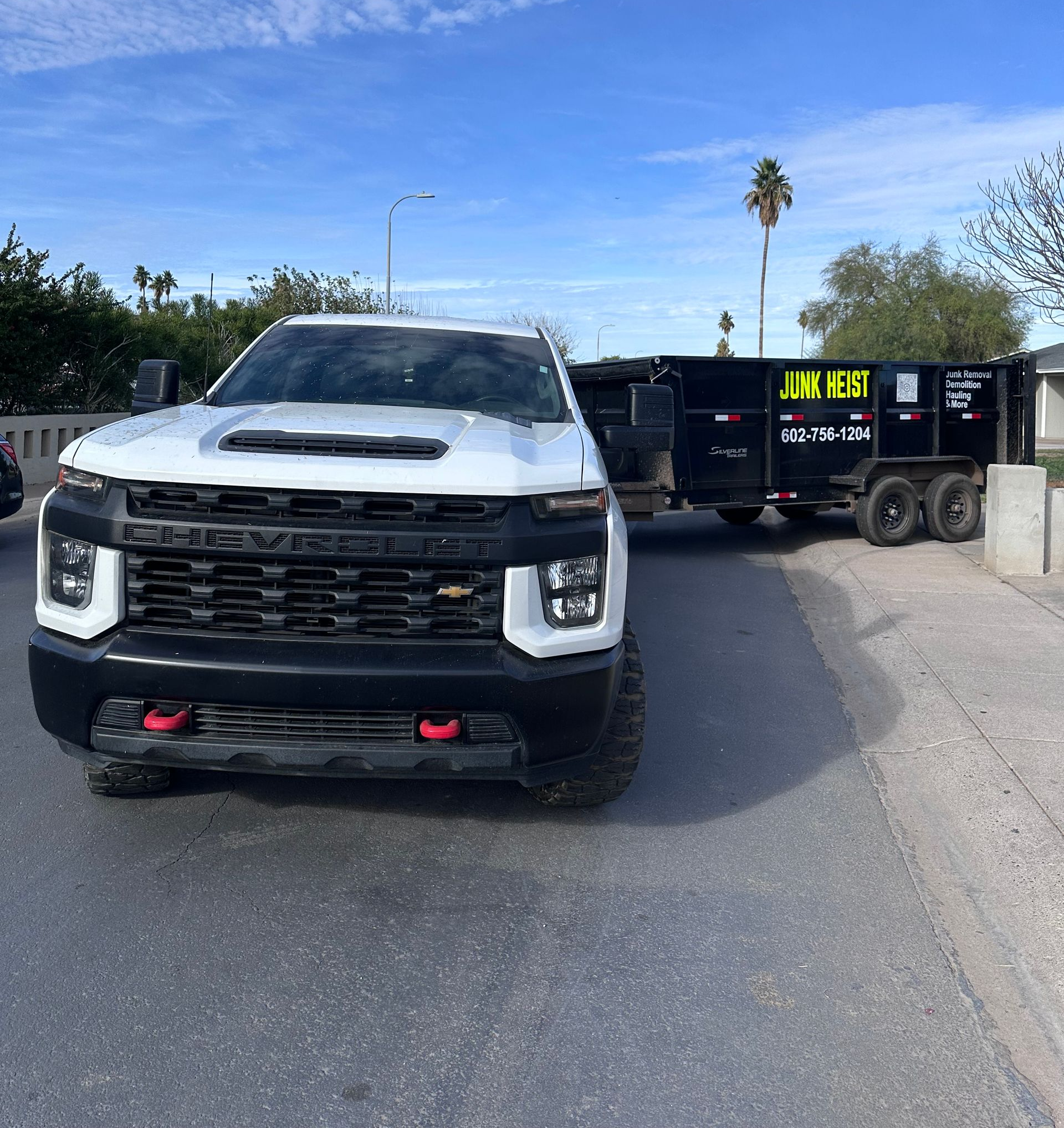 A man is standing next to a white truck in a driveway.