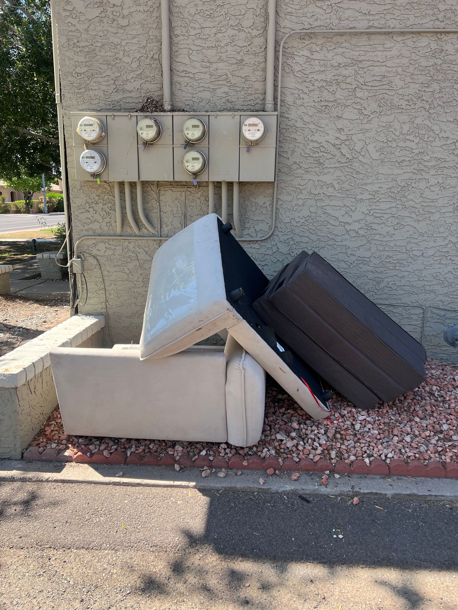 A couch is sitting on the side of the road next to a building.