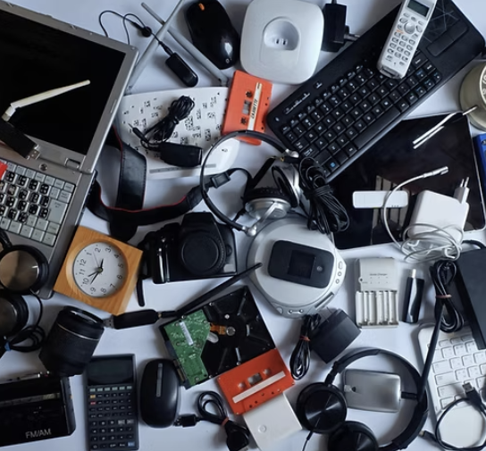 A bunch of electronic devices on a table including a laptop