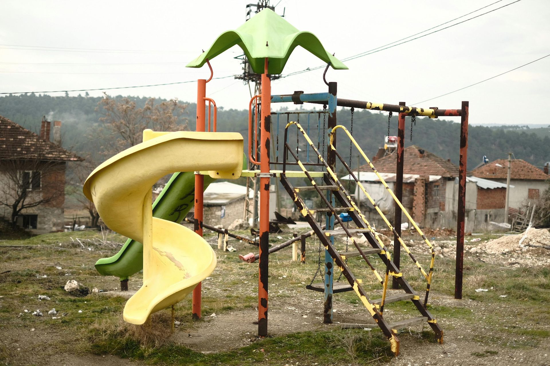 A playground with a yellow slide and a green tower