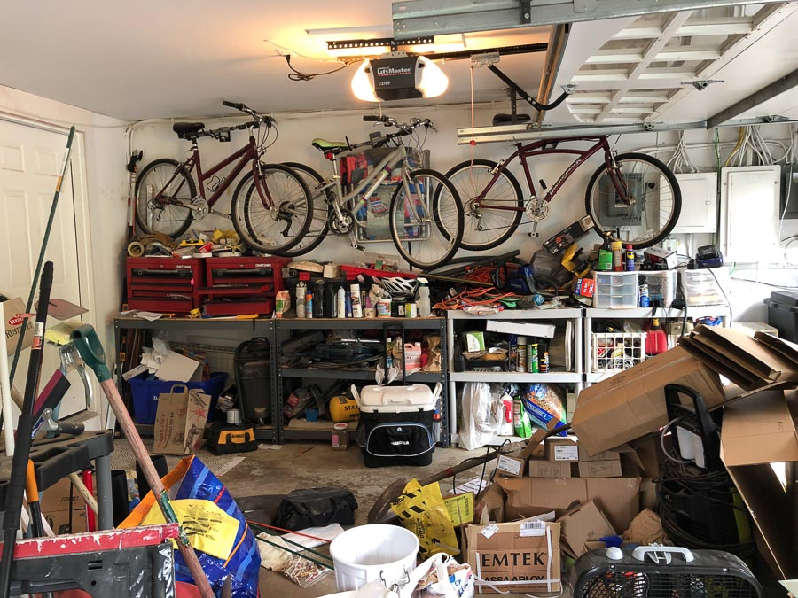 A messy garage with bikes hanging on the wall.