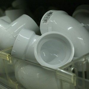 A bunch of white pipes are stacked on top of each other in a plastic container.
