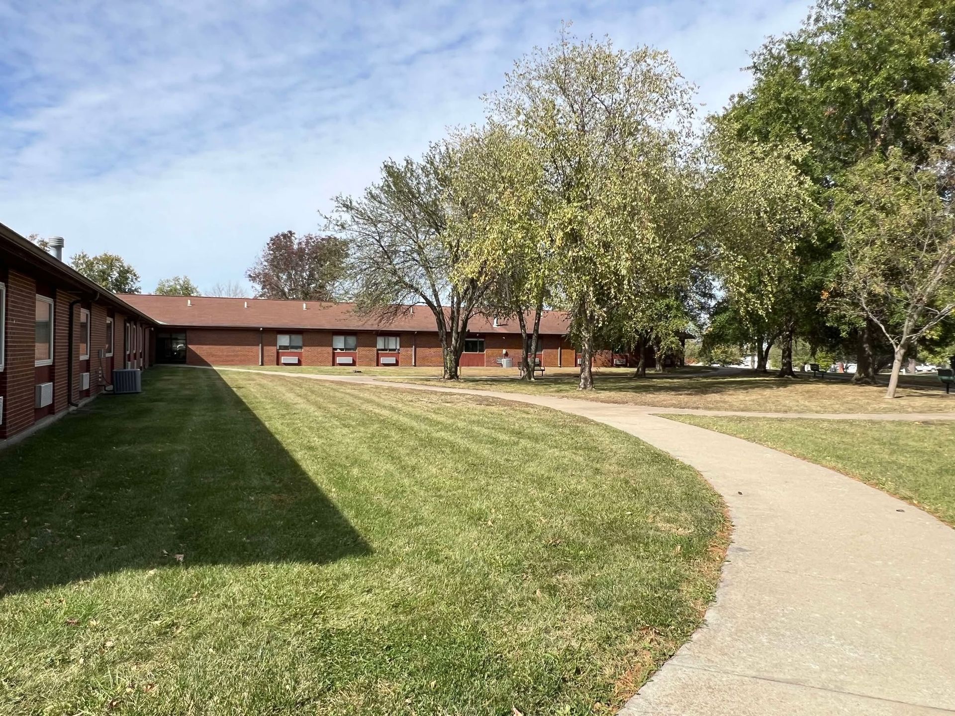 A brick building with a lush green lawn and trees in front of it.