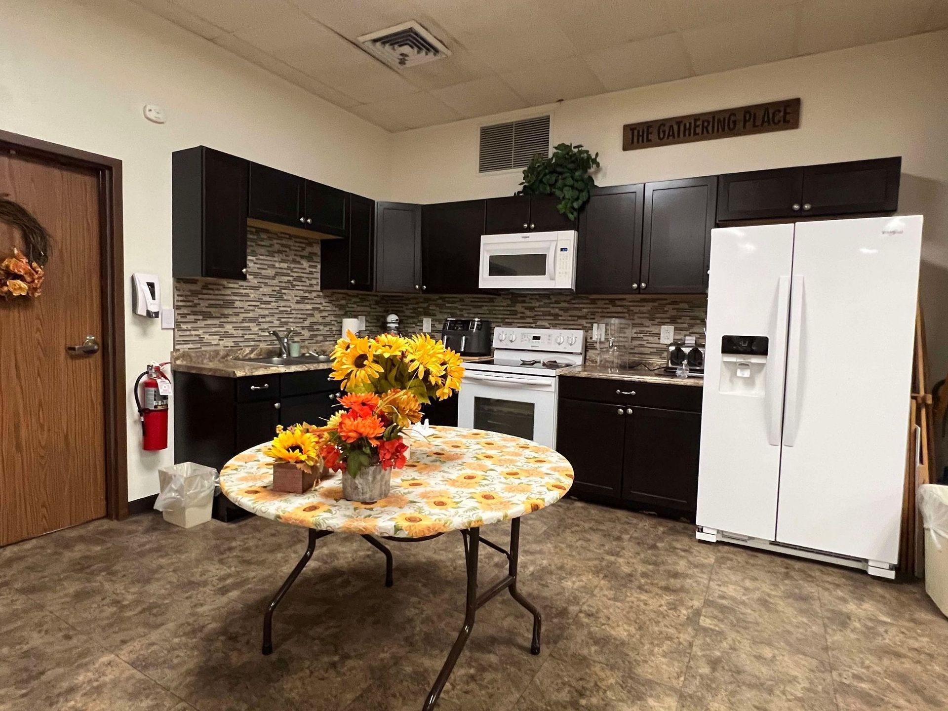 A kitchen with a table and a vase of flowers on it.