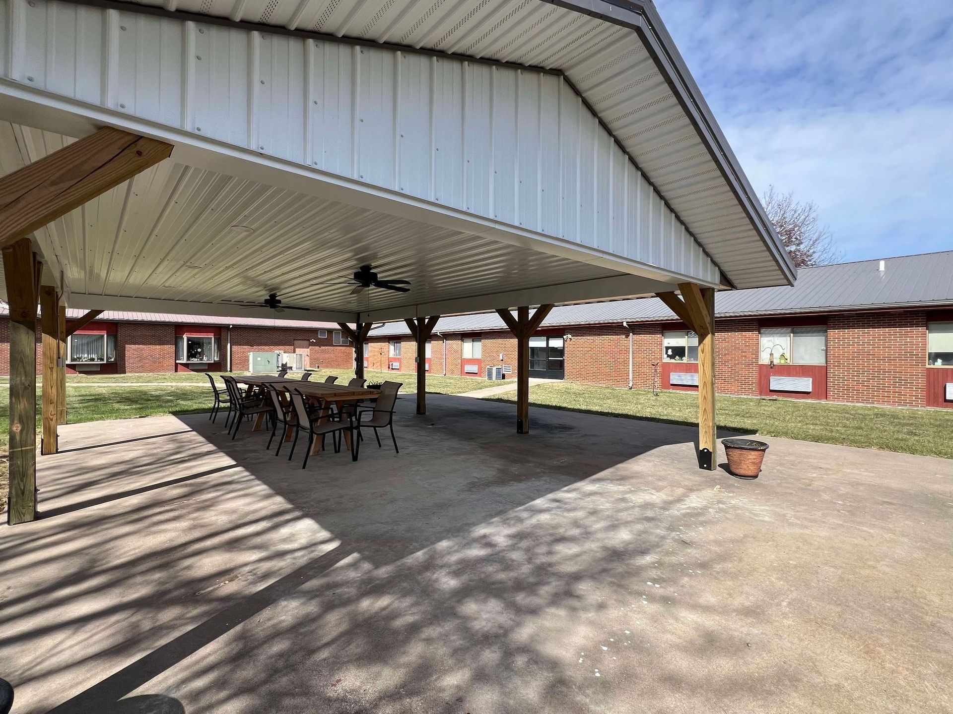 A covered patio area with a table and chairs under a roof.