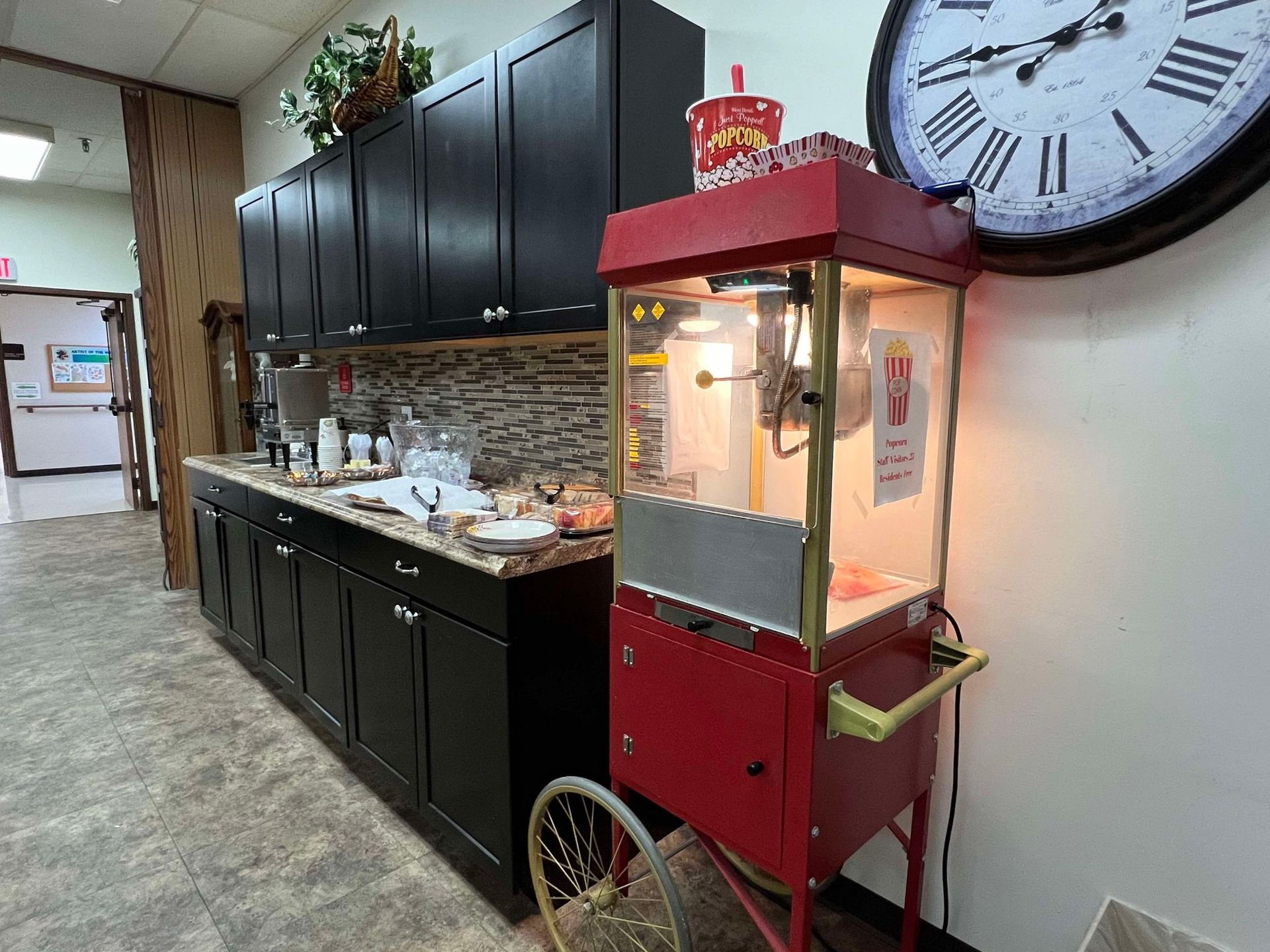 A kitchen with a popcorn machine and a clock on the wall.