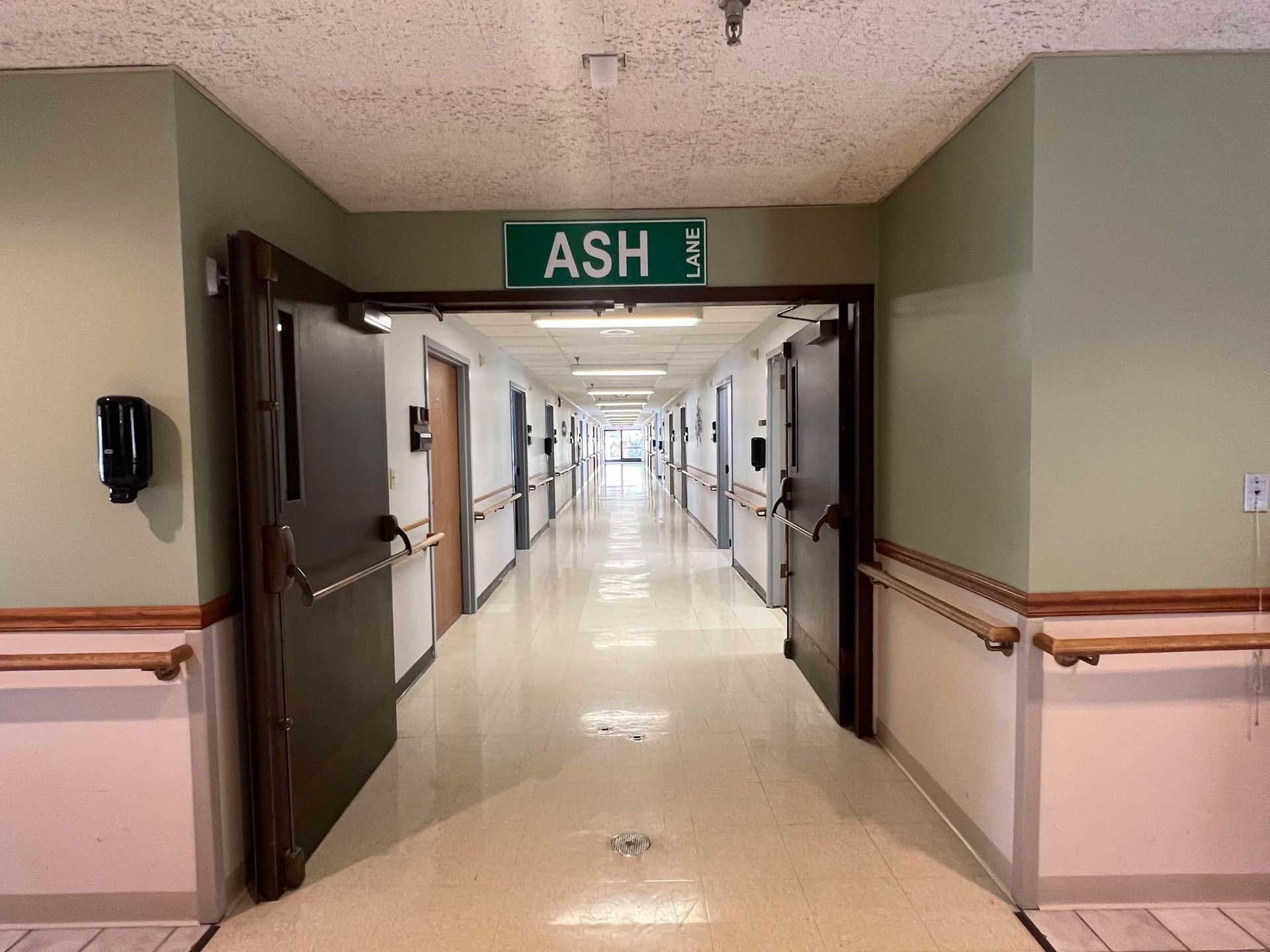 A hospital hallway with a green sign that says ash