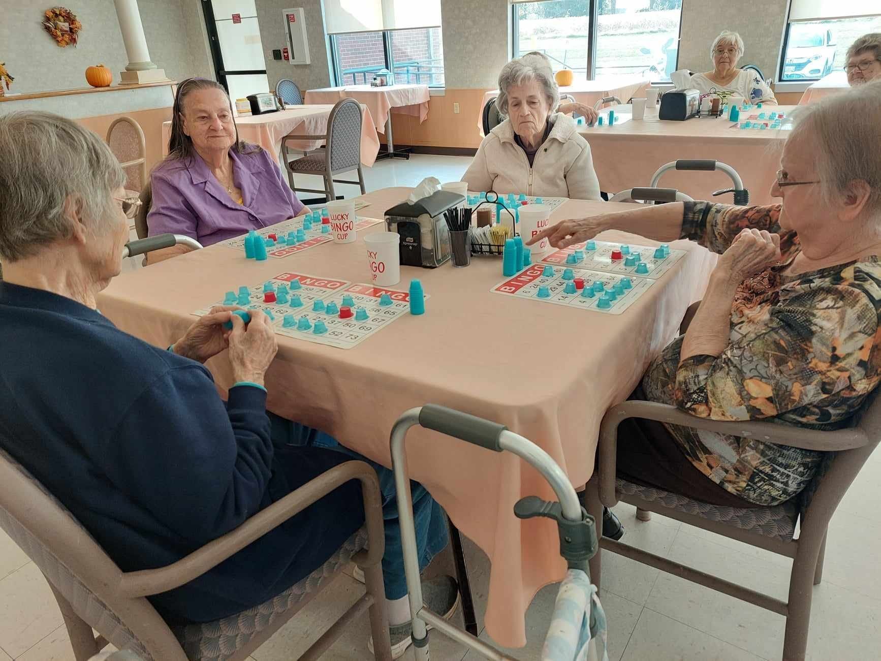 A group of elderly women are sitting around a table playing a game.