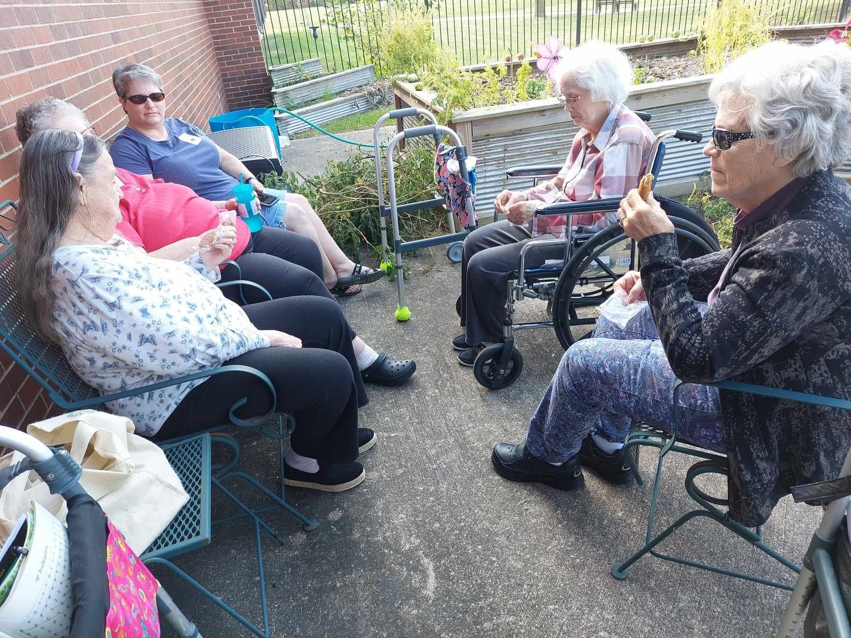 A group of elderly women are sitting in chairs on a patio.