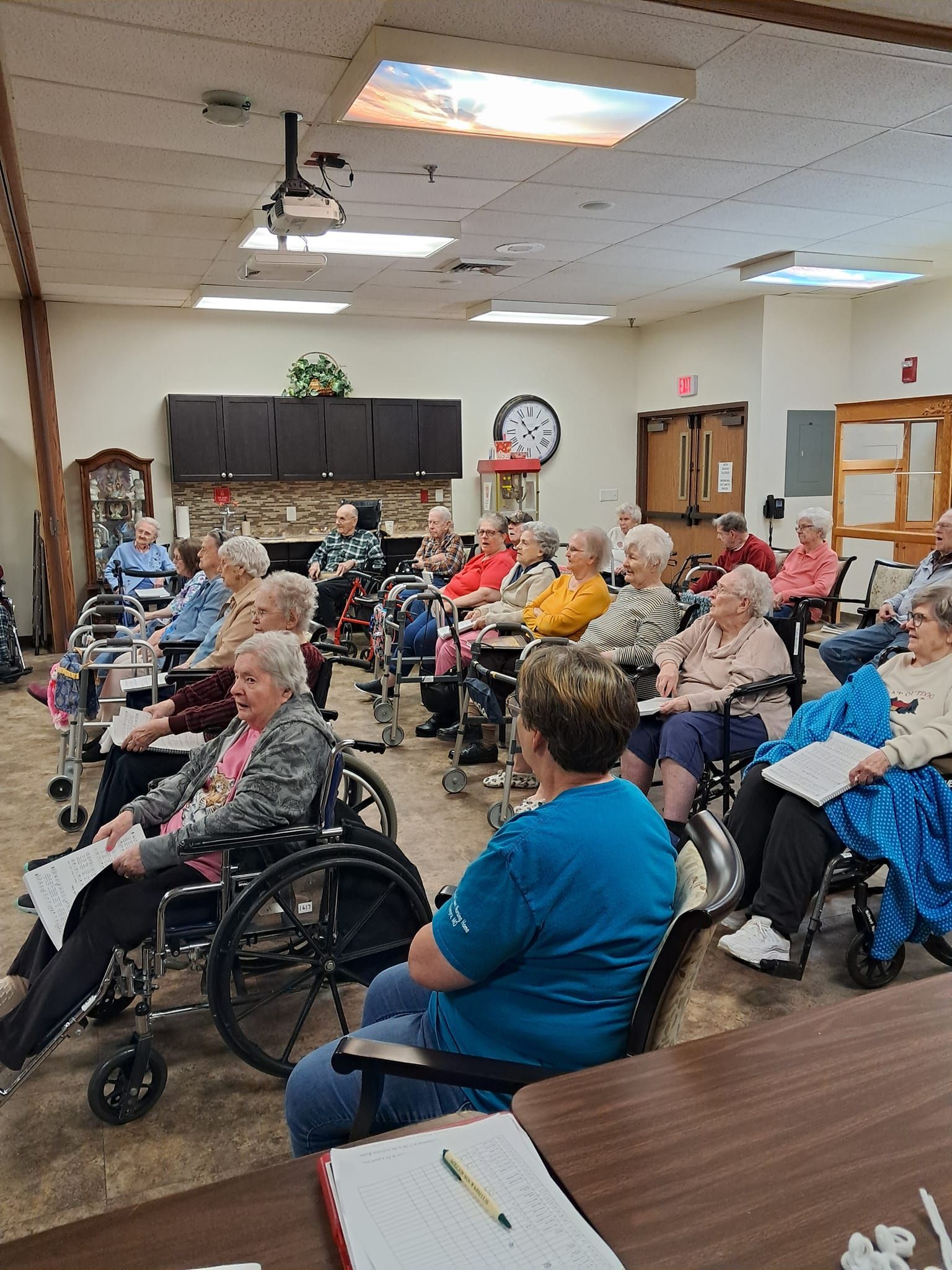 A large group of people in wheelchairs are sitting in a room.