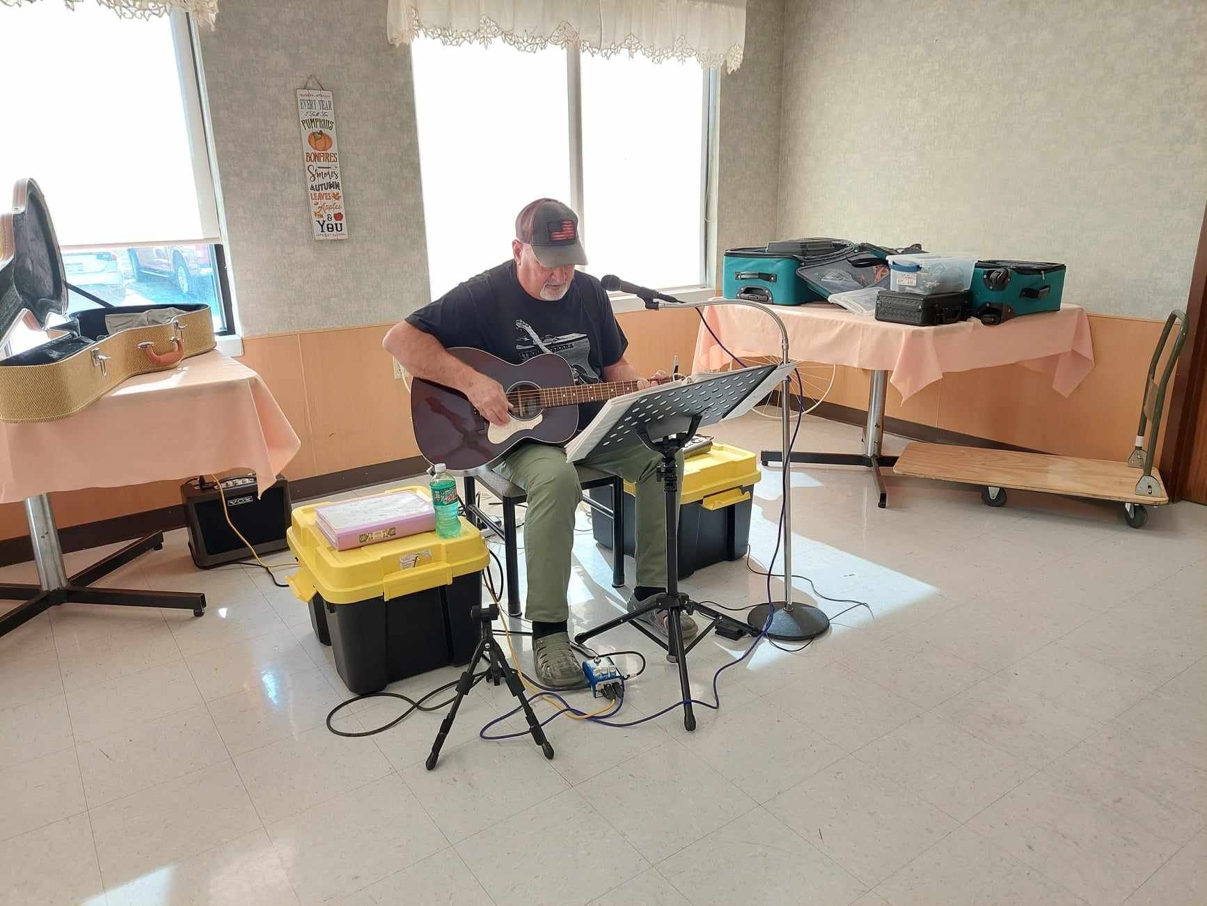 A man is playing a guitar and singing into a microphone in a room.