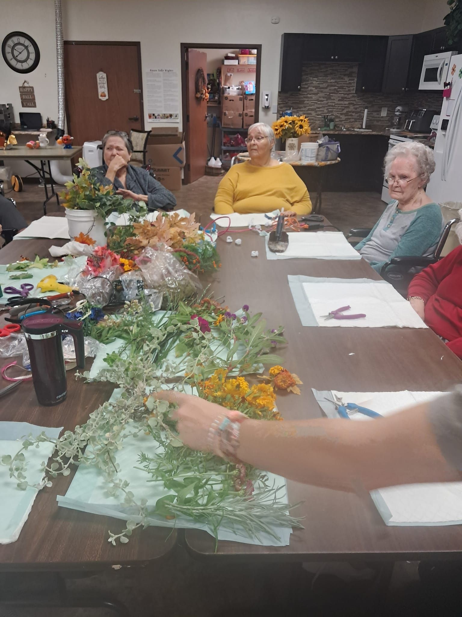 A group of people are sitting around a table with flowers on it.