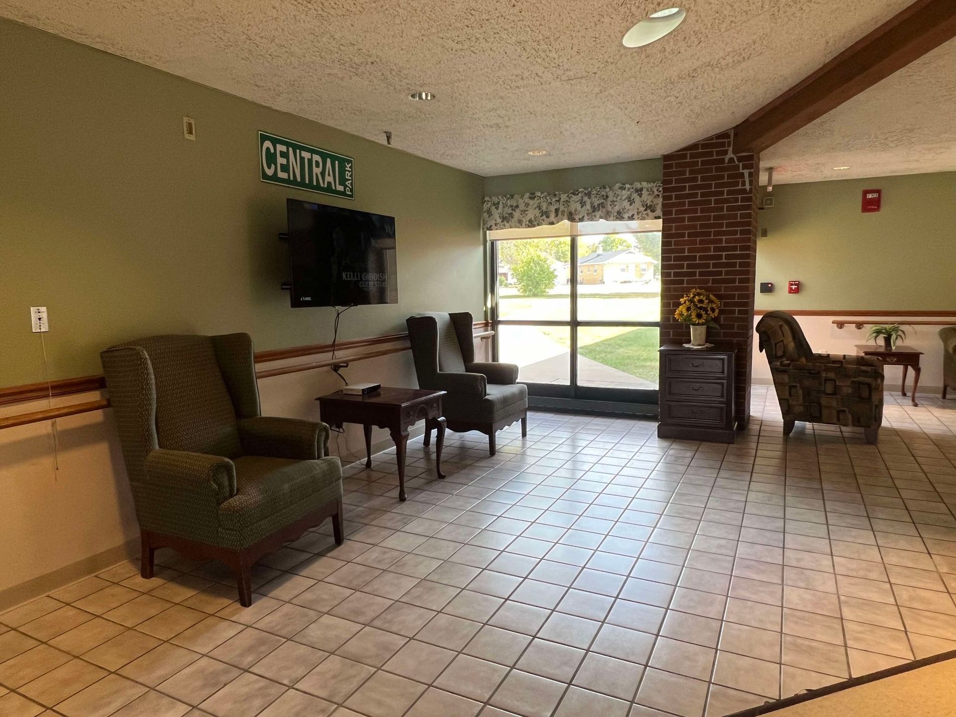 A living room with chairs , a television and a fireplace.