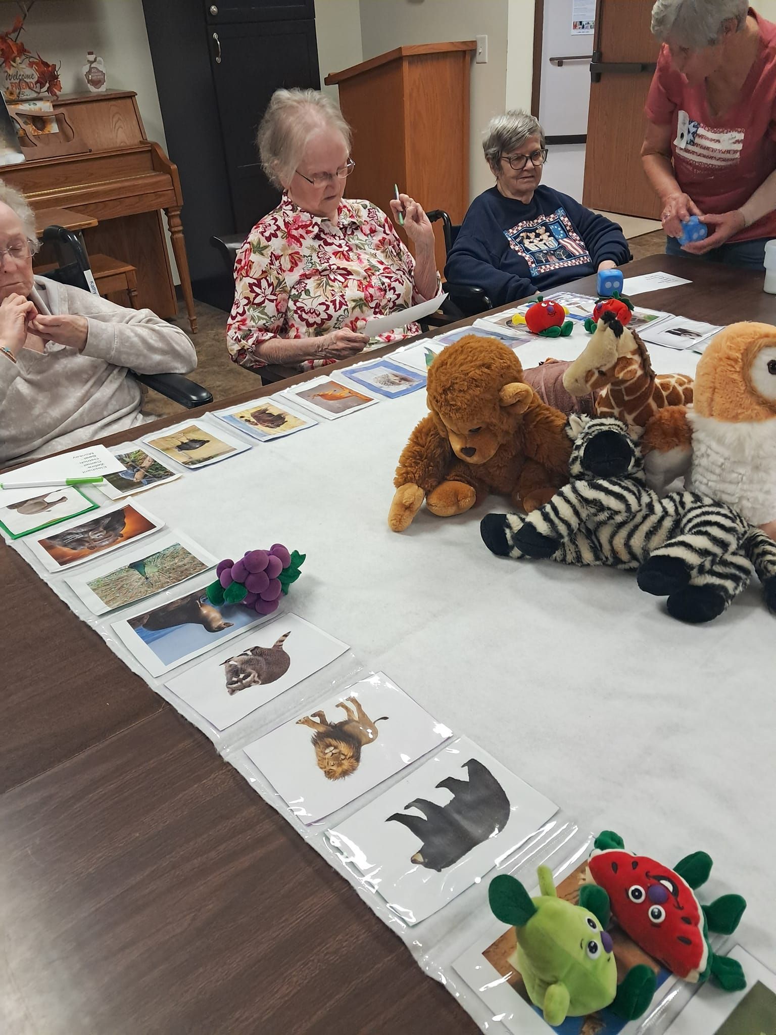 A group of people are sitting around a table with stuffed animals.