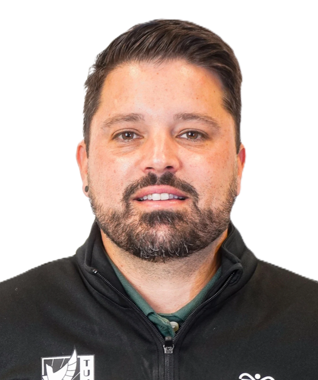 Man with a beard wearing a black and green zip-up jacket, smiling at the camera.