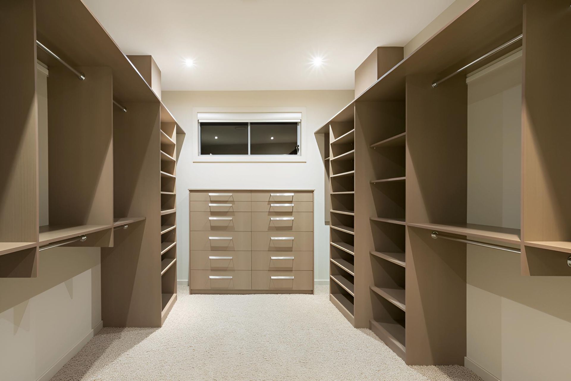 Walk-in closet with tan shelves, drawers, and rods; a small window in the back — CK Cabinetry in Coolum Beach, QLD