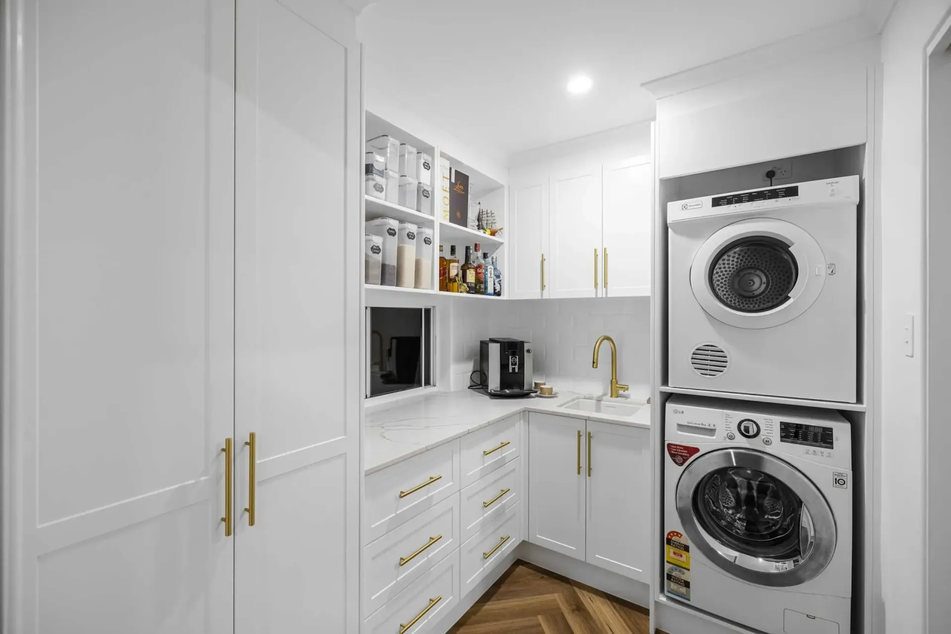 White laundry room with stacked washer and dryer, cabinets, and a small pantry area — CK Cabinetry in Coolum Beach, QLD