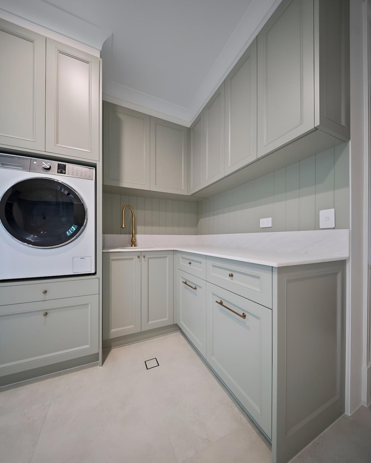 Laundry room with pale green cabinets, white countertop, and washing machine — CK Cabinetry in Coolum Beach, QLD
