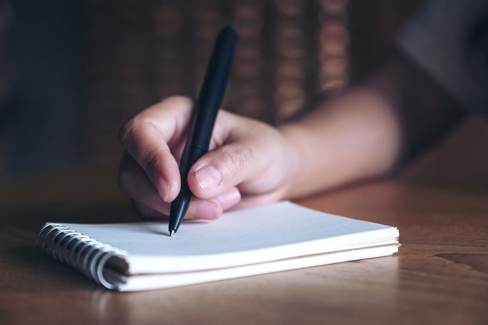 Person filling out tax form 1040, holding pen, palm leaf in background.