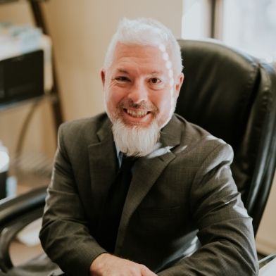 A woman is sitting in the back seat of a car holding a cell phone.