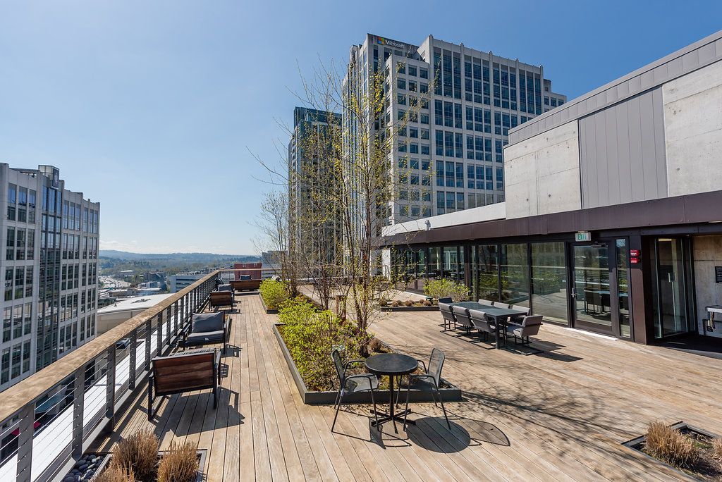 A rooftop deck with tables and chairs and a view of a city.