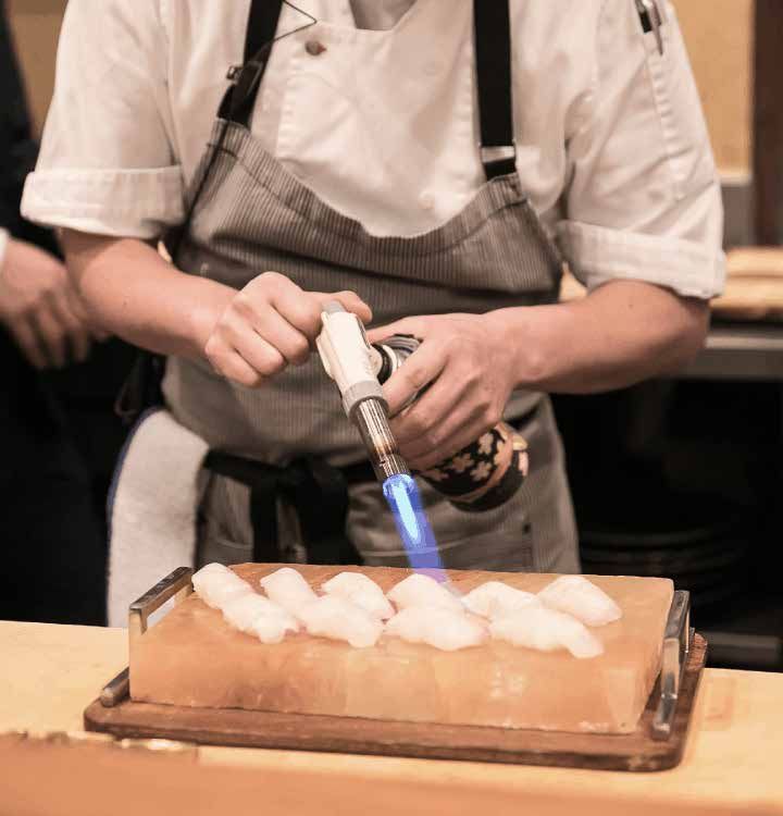 A chef is using a torch on a piece of food.