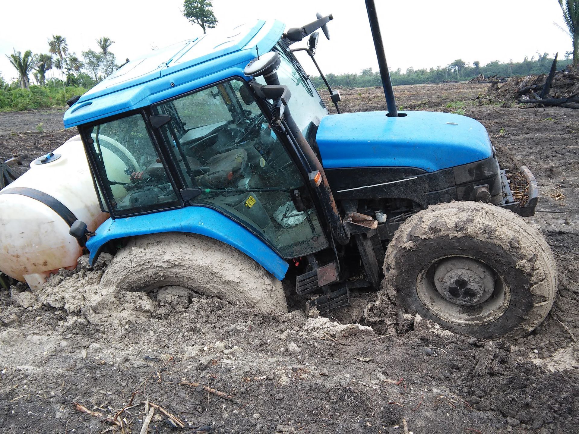 Heavy-duty tractor immobilized in deep mud on a farm, requiring expert tractor towing services.