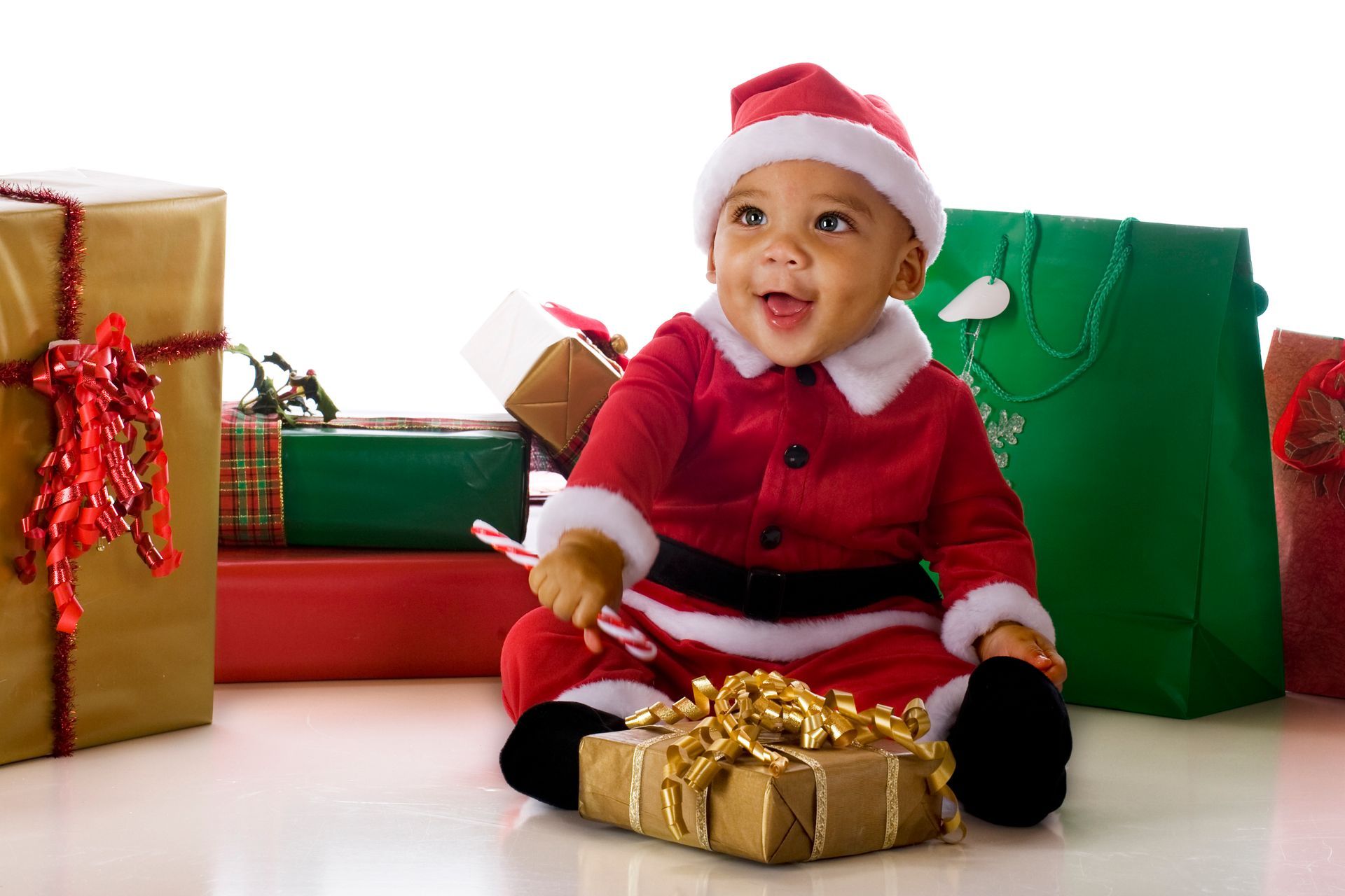 A baby is wearing a santa hat and a red shirt.