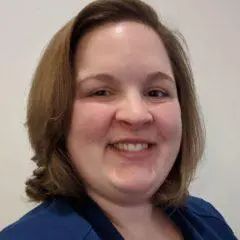A woman in a blue shirt is smiling for the camera.