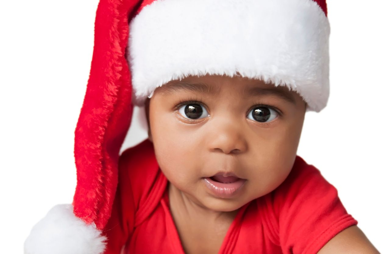 A baby is wearing a santa hat and a red shirt.