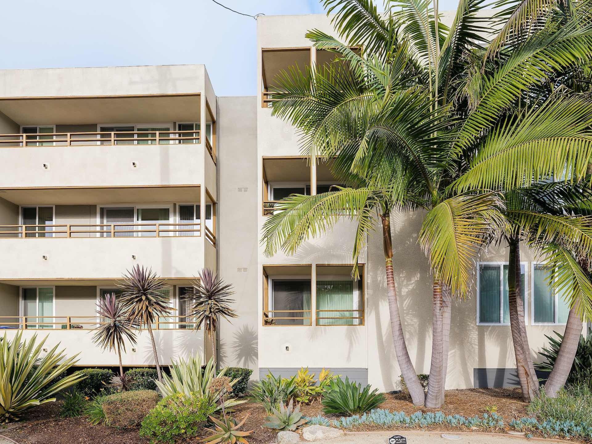 Exterior of apartments with large palm trees adjacent