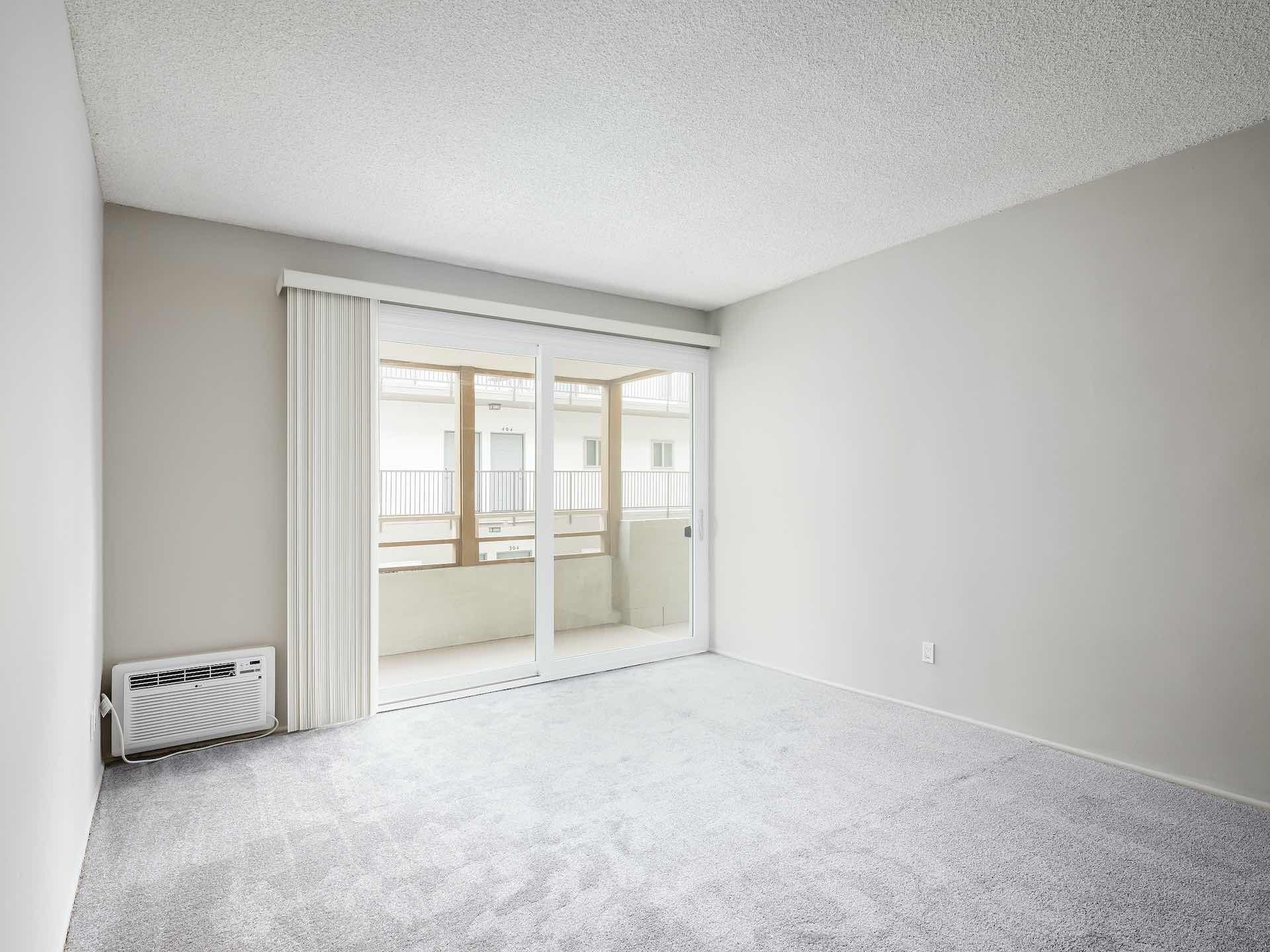 Carpeted bedroom with a.c unit and window