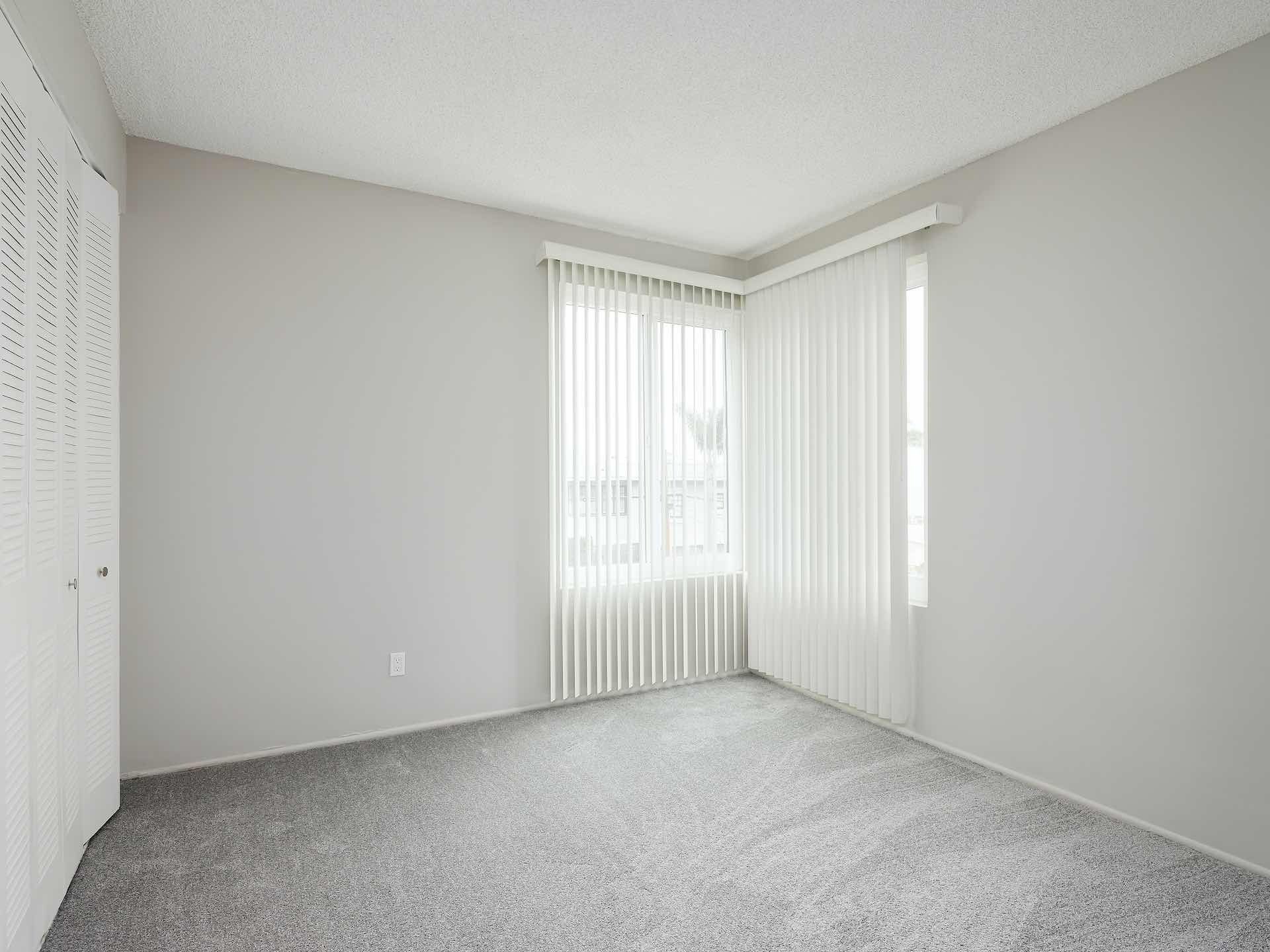 Carpeted bedroom with two large corner windows