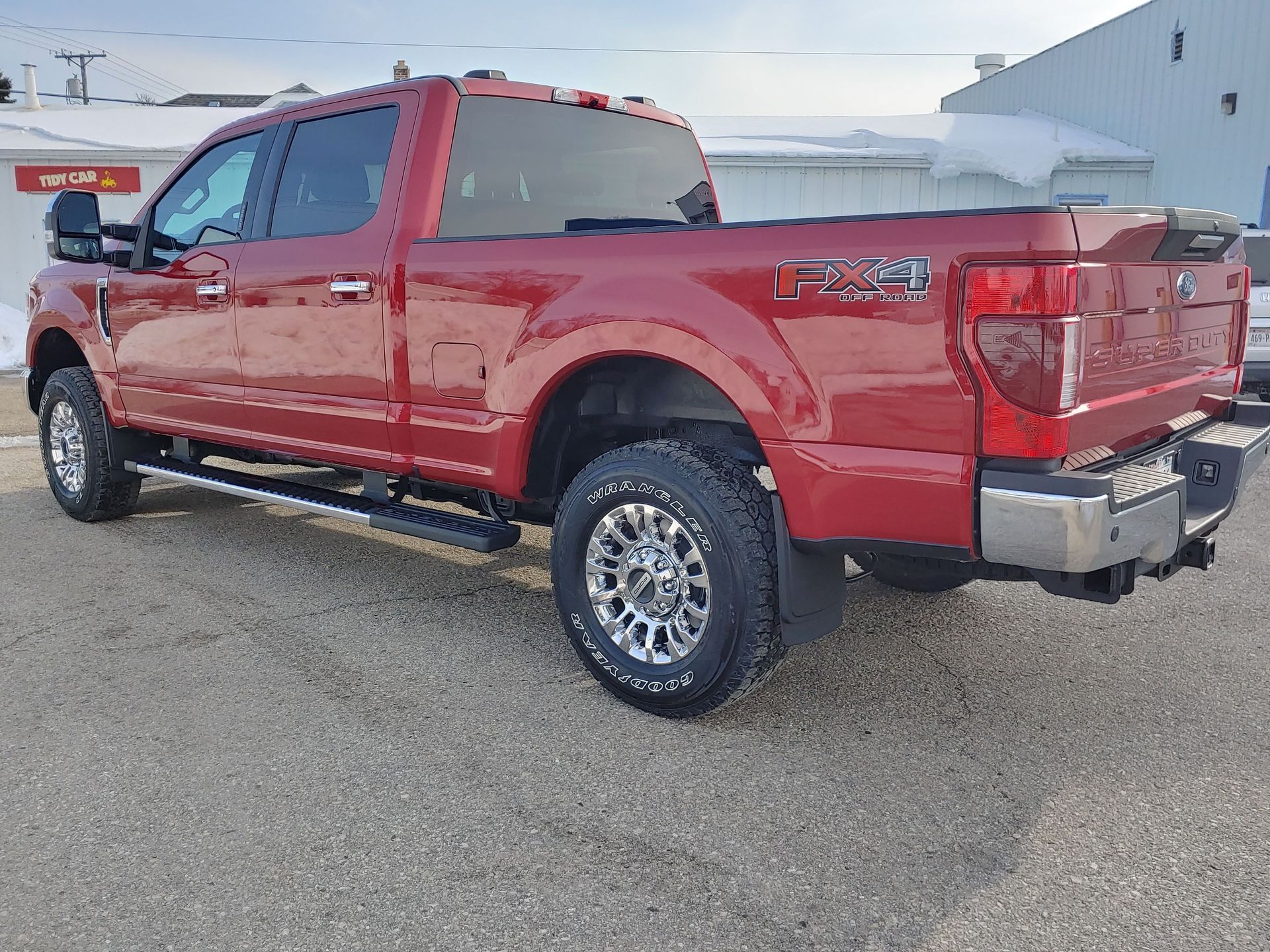A red pickup truck is parked in front of a building.