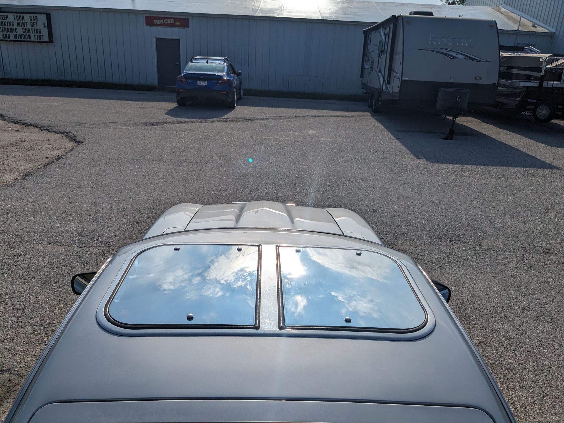 A car with a sunroof is parked in front of a building
