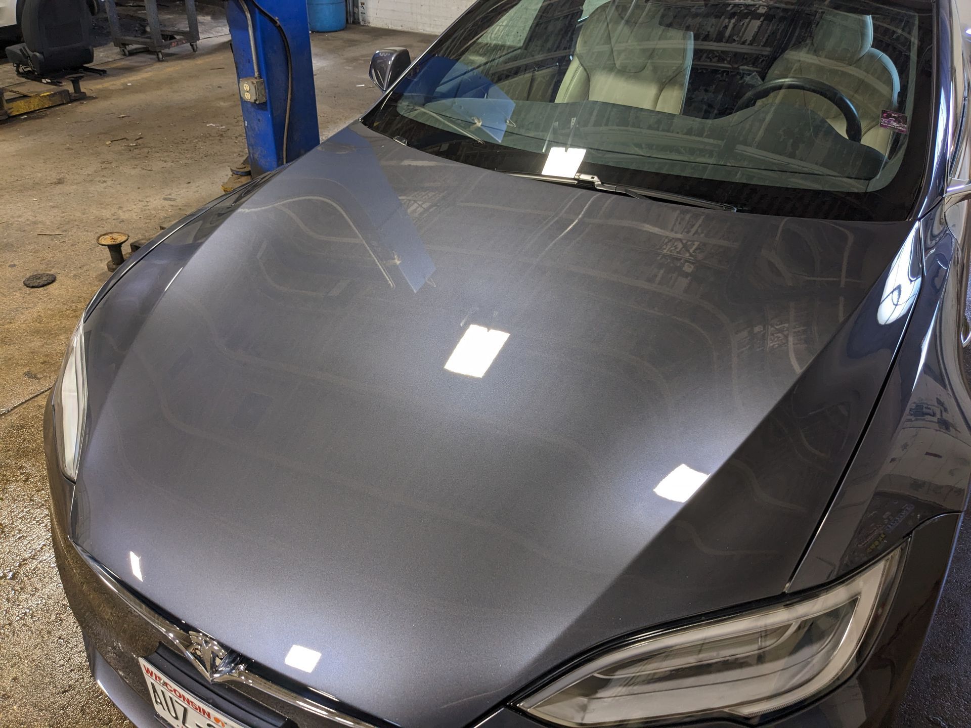 A gray tesla model s is parked in a garage.