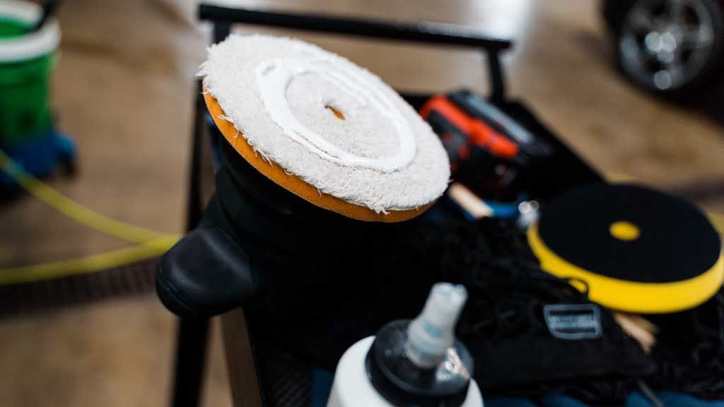 A close up of a polisher and a bottle of polish on a table.