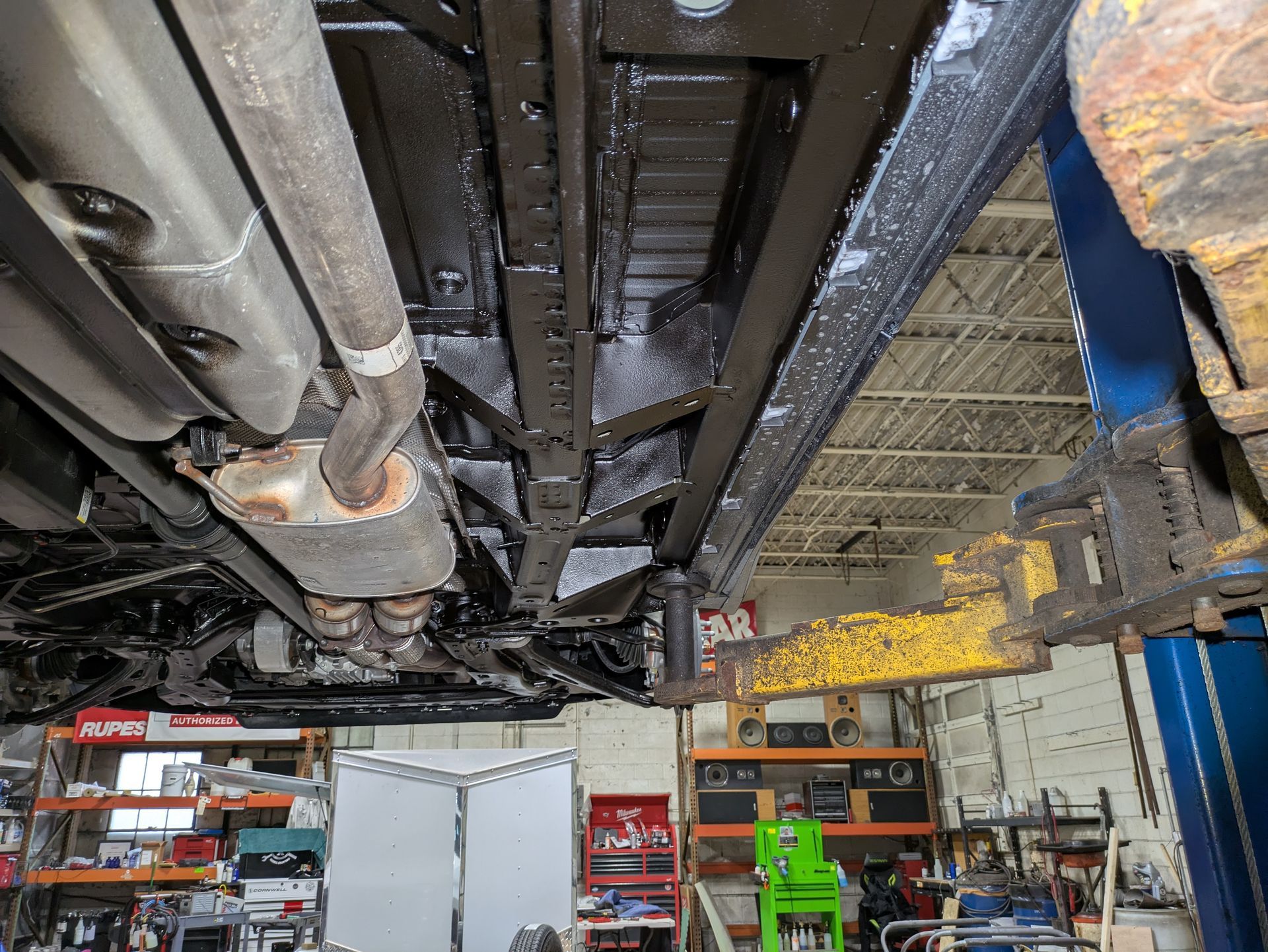 The underside of a car is shown in a garage.
