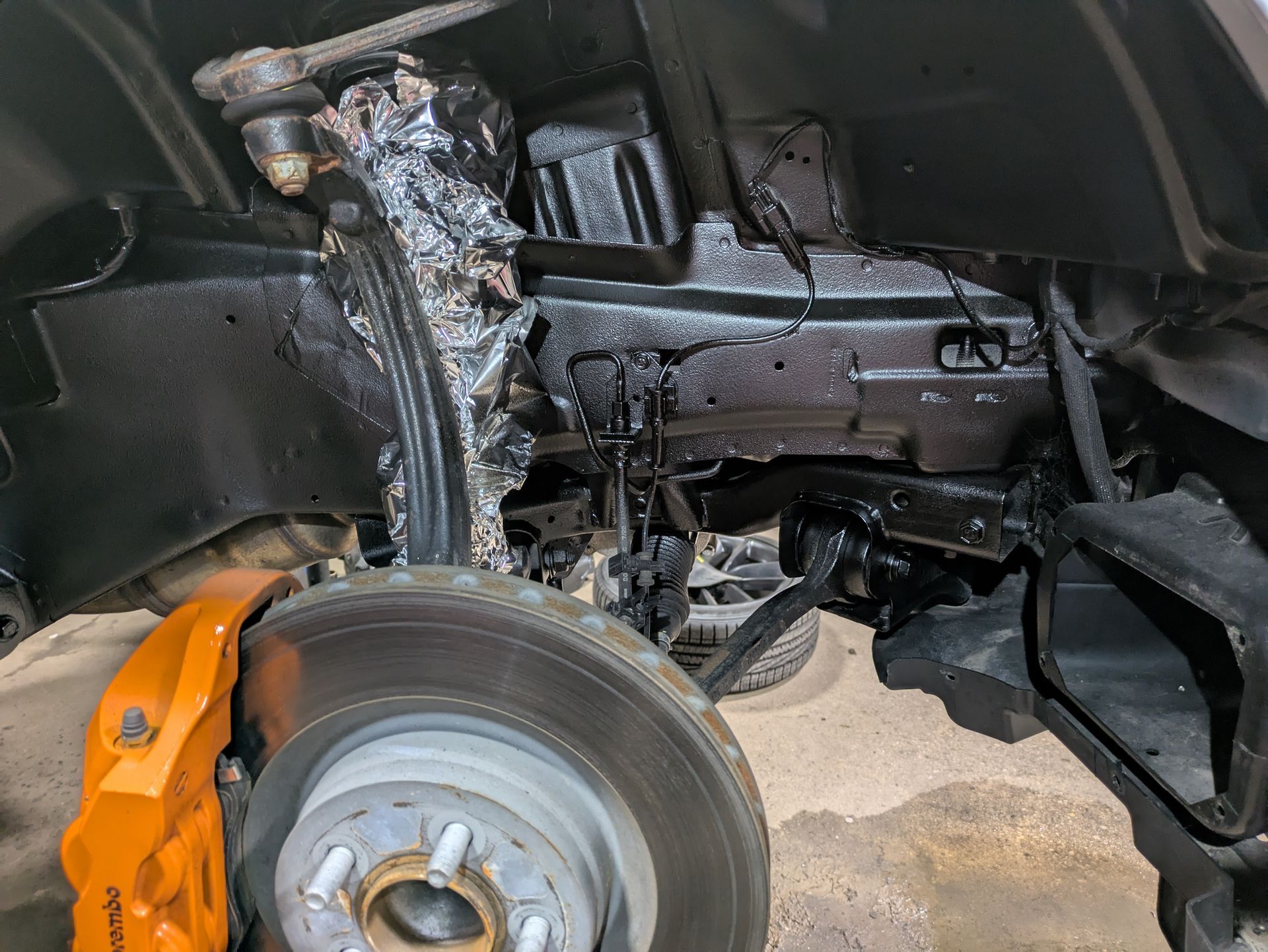 A close up of the underside of a car with a brake caliper on it.