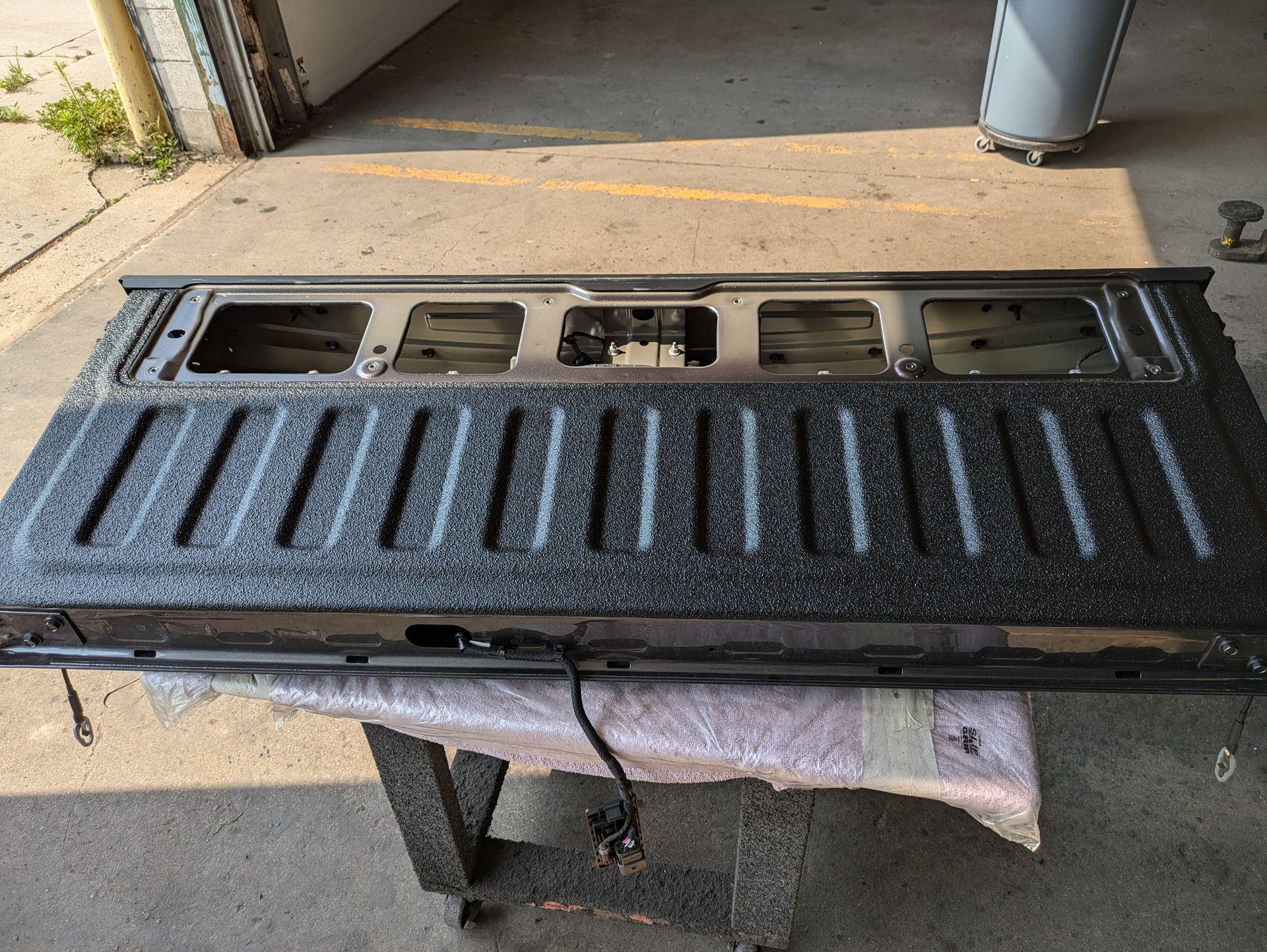 The tailgate of a truck is sitting on a table in a garage.