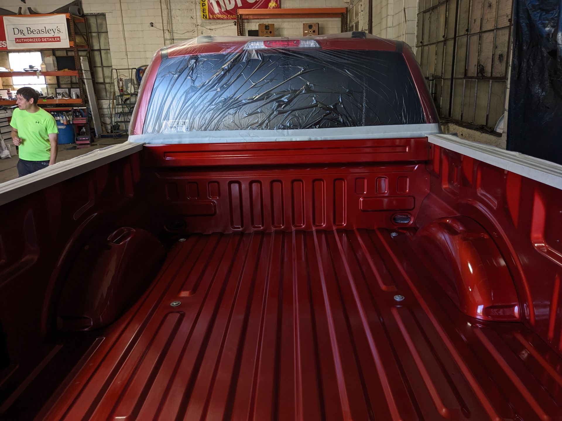 A man in a green shirt is standing next to a red truck