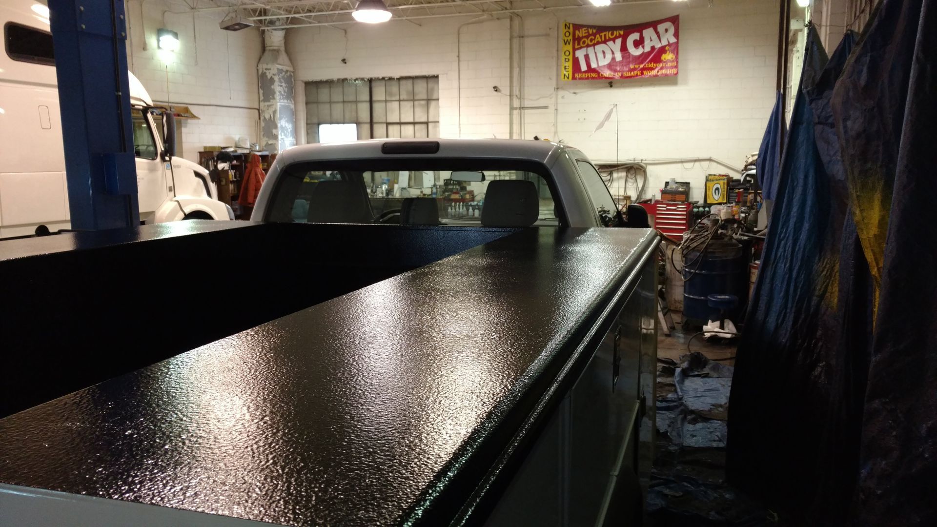 A tiny car sign hangs above a truck in a garage