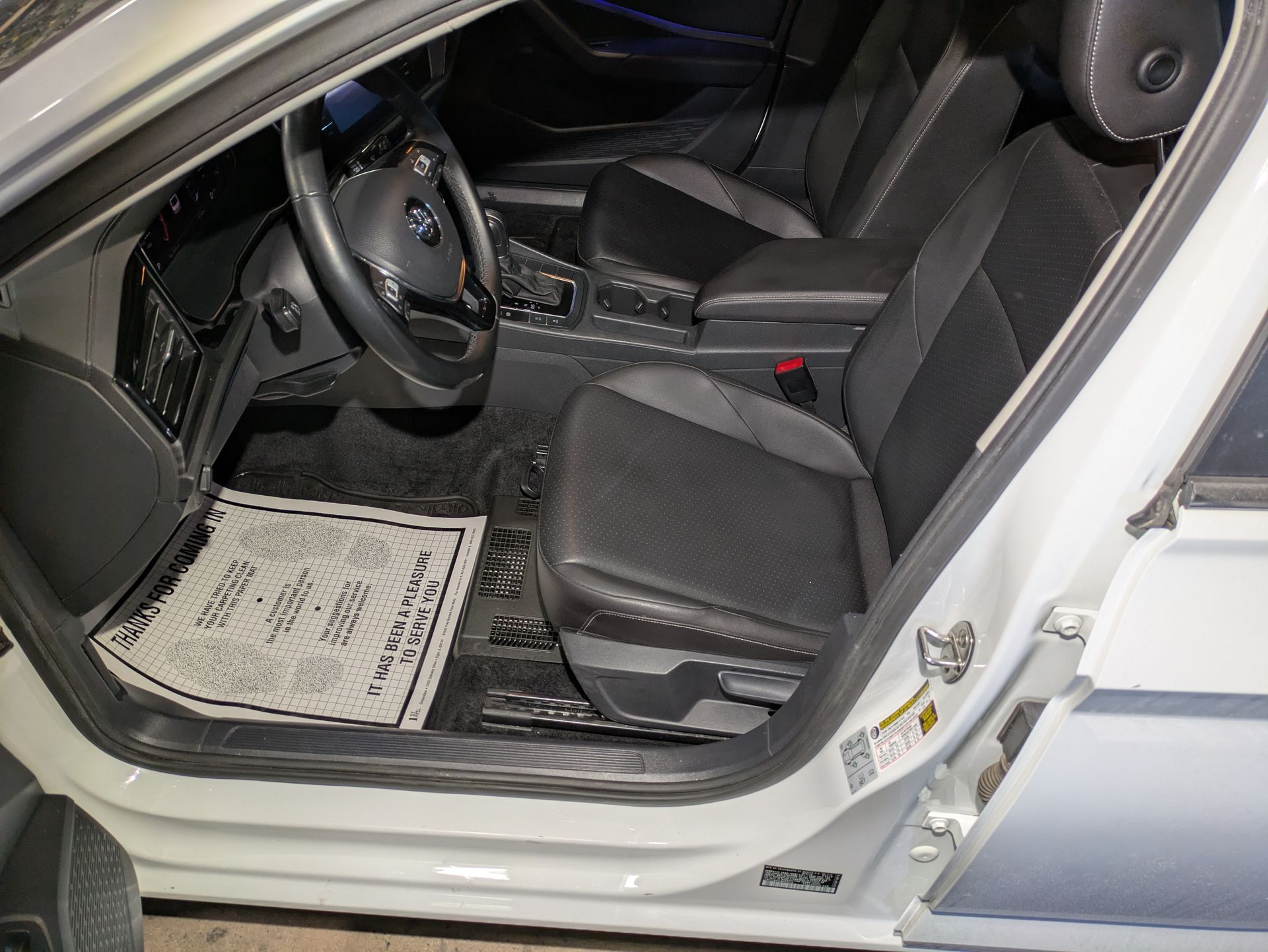 The inside of a white car with the door open.