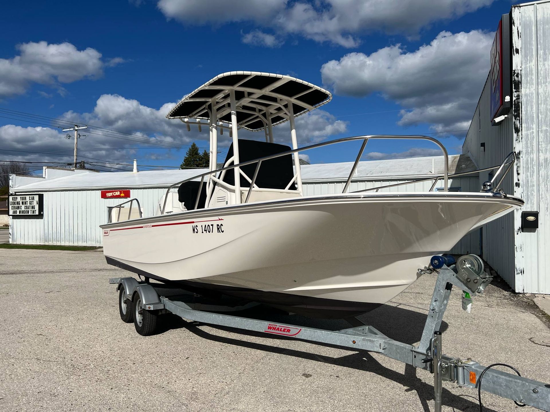 A boat is parked on a trailer in front of a building.