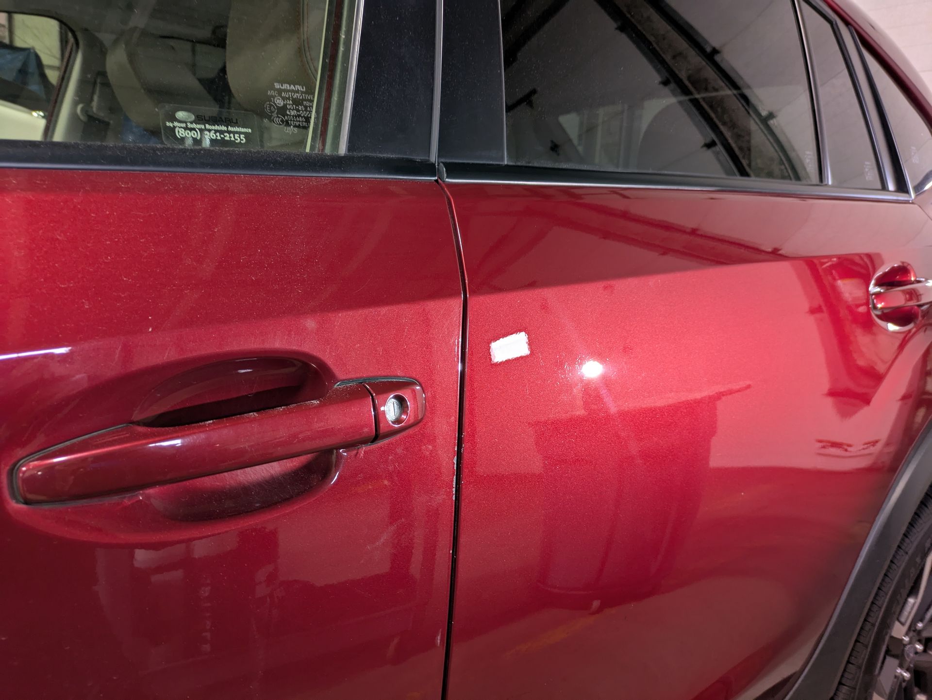 A red car is parked in a garage with the door open.