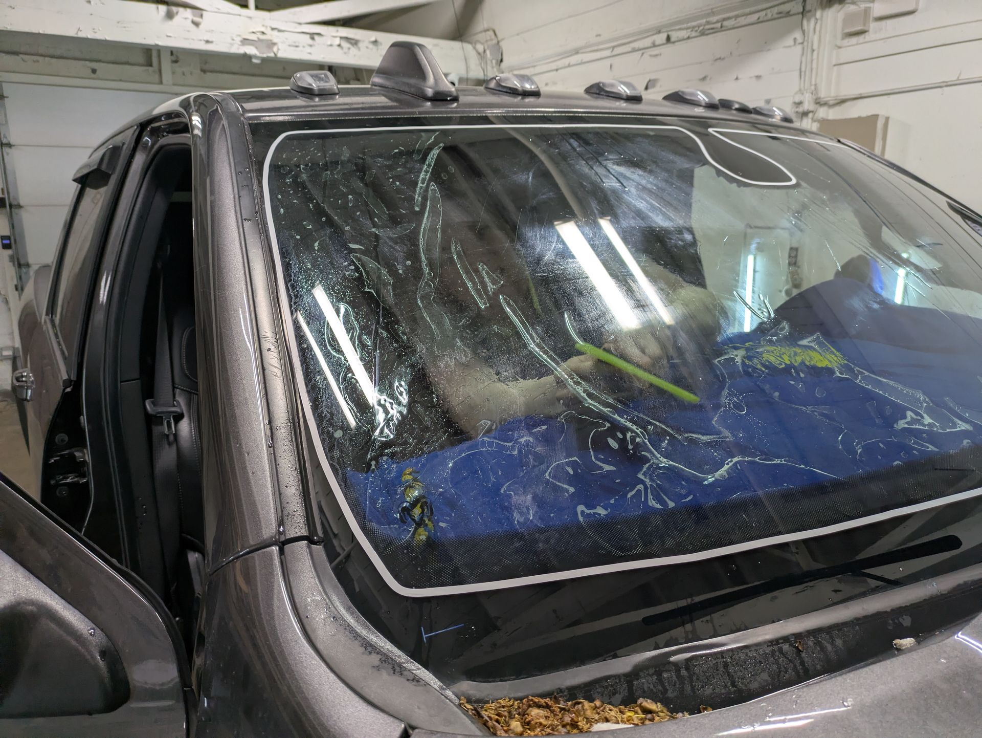 A woman is working on a car window in a garage.