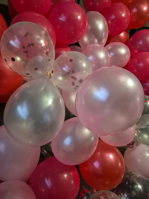 A bunch of pink and red balloons are sitting on a table