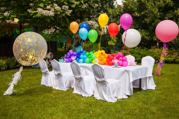 A table and chairs are decorated with balloons for a birthday party.