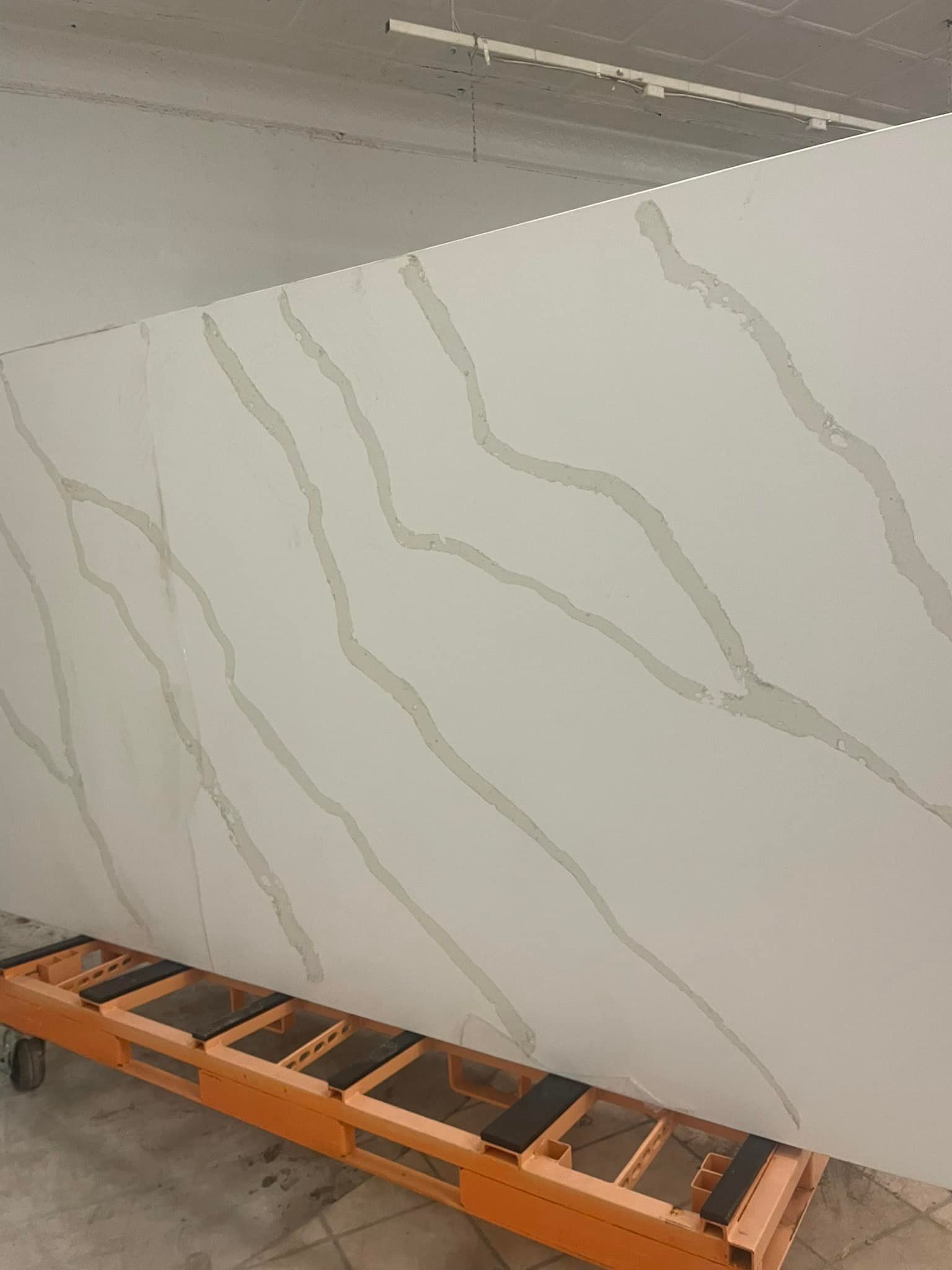 A large white granite slab is sitting on top of a conveyor belt.